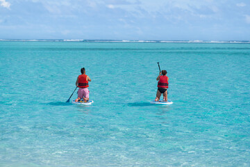 Man and Woman, Couple on Paddle Board on the beach with lifejackets