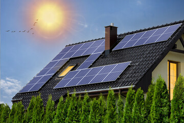 Modern house with solar panels on roof. Photovoltaic panels on roof. Light in windows, green energy...