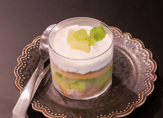Cup parfait with fresh honeydew melon pieces on a golden plate