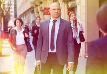 Confident businessman in formal suit walking on city street to office at rush hour