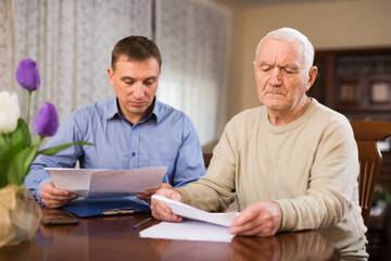 Elderly man and sales manager signing contract of purchase at home. High quality photo