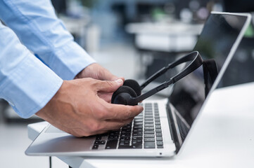 A man puts a headset on a laptop keyboard in the office.