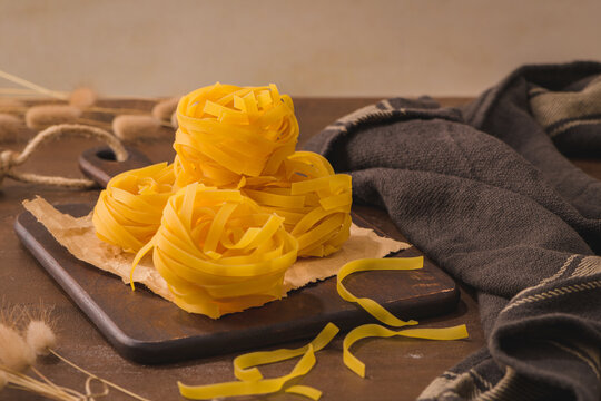 Tagliatelle noodles pasta in wooden cutting board
