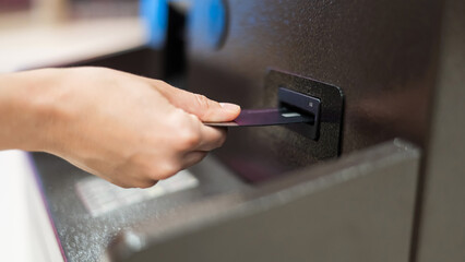 Faceless woman inserts bank card at ATM. 