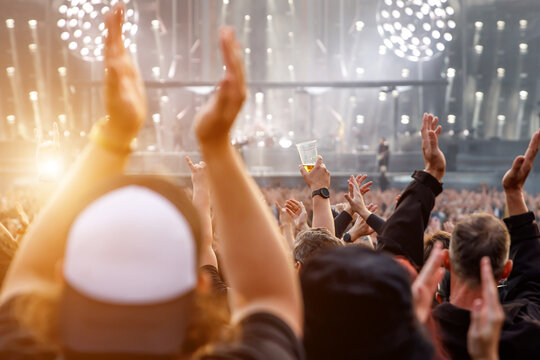 The crowd at a concert. People with raised hands on the dance floor.