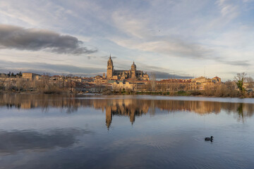 Fototapeta na wymiar Sunset from the Ledesma river and in the background the cathedral of Salamanca reflecting in the water.