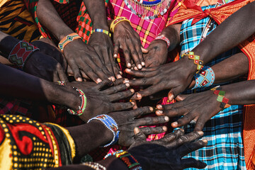 Fototapeta Hands of Maasai Mara tribe people putting together showing their bracelet obraz