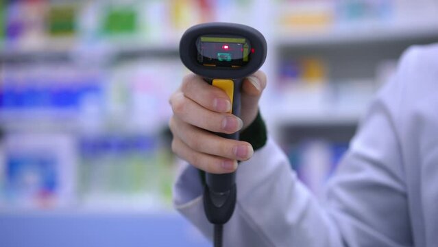 Front view close-up bar code reader in female hand with red light flashing. Unrecognizable woman pharmacist scanning QR code in drugstore in slow motion