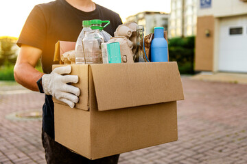 a man carries garbage in a box for sorting. The concept of caring for the environment and ecology