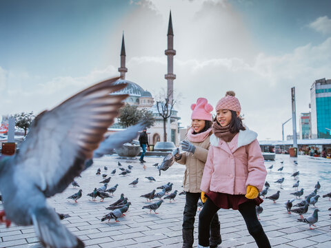 happy kids playing with pigeons in taksim square turkey during winter