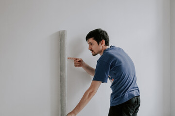 Caucasian plasterer man checks the evenness of the walls after puttying.