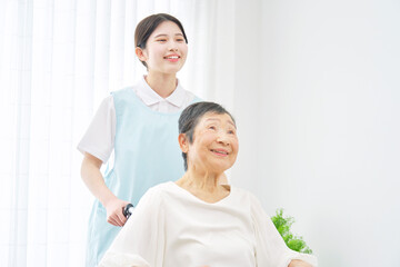 介護施設でシニア女性の乗る車椅子を押す介護士