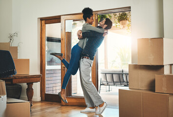 Joyful interracial couple moving in to a new home together hugging feeling happy and excited. Diverse, loving and young lovers relocating to a house and celebrating by embracing