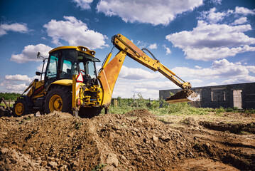 Excavator working at house construction site - digging foundations for modern house. Beginning of house building. Earth moving and foundation preparation.