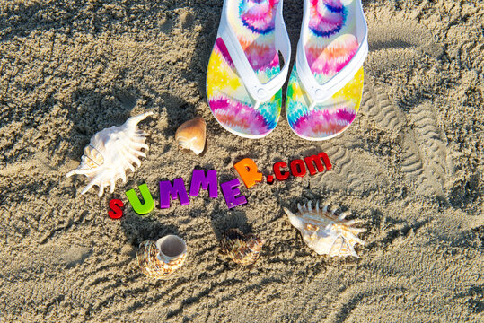 Beach slippers on the sand of the beach, shells and letters SUMMER. Vacation and summer vacation concept.