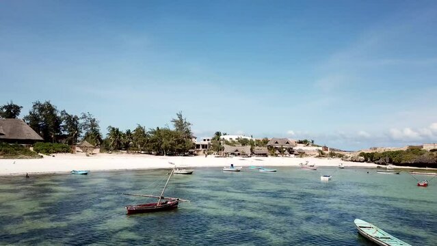 Drone flyover fishing boats at Watamu coast. Tropical scenery of sandy beach and resort in Kenya.