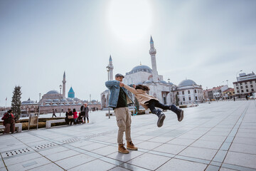 father spinning around his daughter while playing in city square in konya turkey