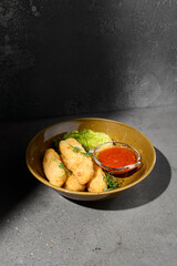 Fototapeta na wymiar Cheese sticks in minimal style on gray stone background. Fried Cheese with spicy sauce on concrete table with hard shadow. Mozzarella sticks on dark stone background. Minimal menu concept.
