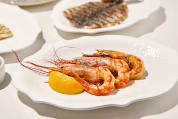 Grilled shrimps on light background with shadows. Grilled prawns with lemon on white table. Aesthetic composition with bbq shrimps. Bbq prawns. Grilled seafood. Summer menu.