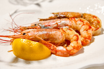 Grilled shrimps on light background with shadows. Grilled prawns with lemon on white table. Aesthetic composition with bbq shrimps. Bbq prawns. Grilled seafood. Summer menu.