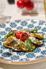 Grilled vegetables on light background with shadows. Salad with grilled zucchini, eggplant and tomatoes. Aesthetic composition with bbq vegetables. Vegan food. Grilled vegetables in Summer menu.