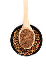 Ground dried sumac berry powder in a wooden scoop over a bowl of whole dehydrated berries