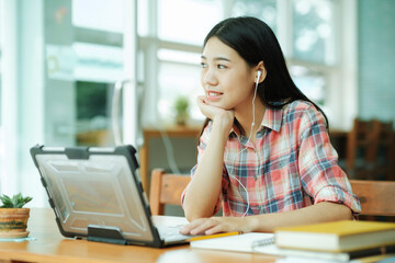 Obraz premium Young asian woman study in front of the laptop computer and and using headphones at offsite..