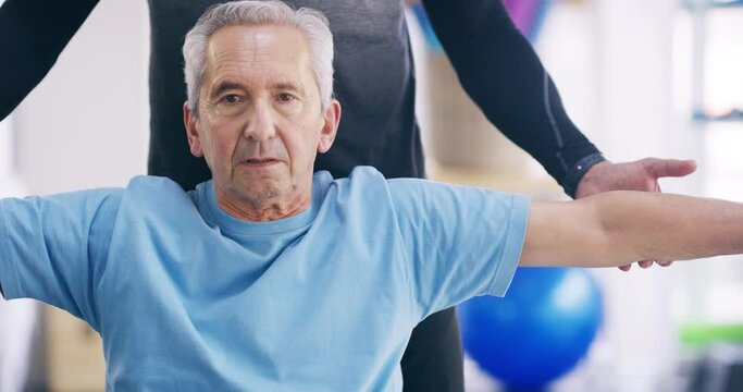 Senior man exercising, doing physical activity and recovering from an injury with the help of a physiotherapist in a gym. Portrait of a retired male doing a workout with a trainer at a sports center