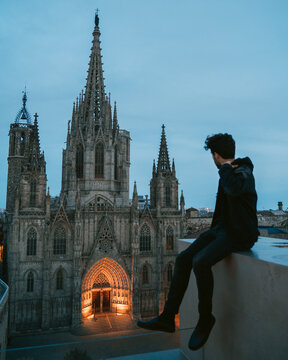 Young millennial adult on a rooftop in a risky situation daredevil looking at  Barcelona Cathedral 