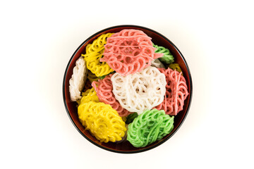 Raw multicolored tapioca crackers in an orange bowl top down isolated over white