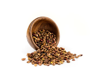 Whole dried sumac berries  spilling out of a small wood bowl over white