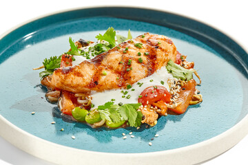 Healthy food - baked salmon steak with tomato salad and white sauce. Roast salmon with vegetables on contemporary plate in asian style. Restaurant dish - salmon filet with hard shadow.