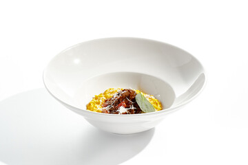 Risotto alla milanese with meat ragu. Saffron risotto with lamb meat isolated on white background. Yellow risotto in white plate. Italian classic cuisine in restaurant menu.