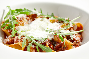 Italian pasta pappardelle with bolognese sauce  and parmesan isolated on white background. Pasta tagliatelle with meat ragu and creamy espuma with arugula. Minced beef in tomato sauce with pasta.