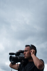 Obraz premium Man filming with a big video camera in a cloudy day