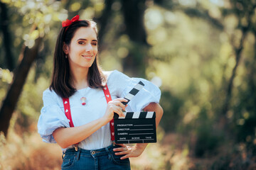 Happy Actress Holding a Cinema Clapper in the Forest. Cheerful movie protagonist starring in...