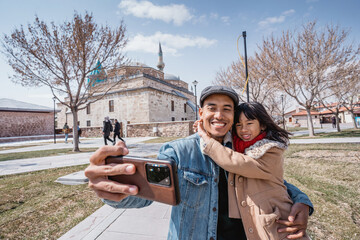father taking selfie with his daughter with mevlana museum as a background