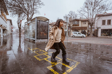 girl playing hopscotch on sidewalk during winter and snow fall