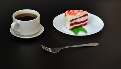 A piece of red velvet cake on a plate and a cup of black coffee, the whole composition is on a...