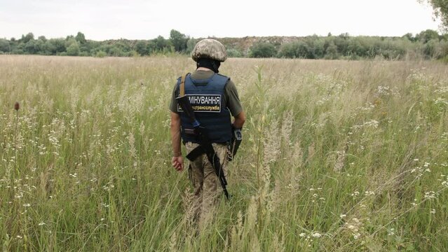 Translation: Mine clearance. Military service. Soldier using mine detector, neutralizing mines, disarms a mine, soldier removes mines, examining territory with a metal detector