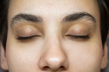 Close-up portrait of a young caucasian woman before eyelash lamination procedure. 