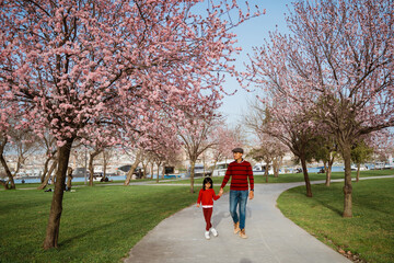 Fototapeta premium happy father and daughter looking at cherry blossom in the park