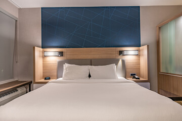 Interior evening photo of a typical US hotel room with a Queen size bed.	