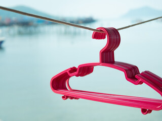 Pink plastic clothes hangers hang outside the balcony of the house. Home appliances for clothes.