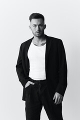 Fototapeta premium Modelling snapshots. Evil self-confident attractive handsome man in classic suit hold hand on pocket posing isolated in white studio background. Black and White concept. Fashion offer. Copy space