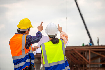 Female engineer and foreman worker checking project at building site, Engineer and builders in...