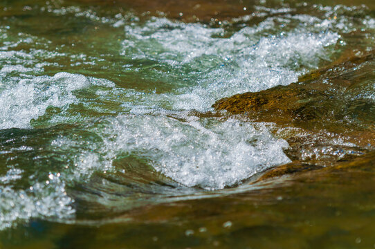 A closeup of rocks in a rapid on the Guadalupe River in the Texas Hill Country. with the water flowing and churning making a backdrop or environmental example image with space for text.
