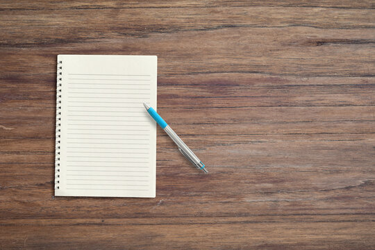 Blank White Notebook Pad On Wood Desk Background With Copy Space. Top Down