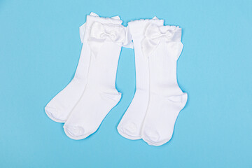 high white children's socks with big bows for festive clothes on a blue background top view