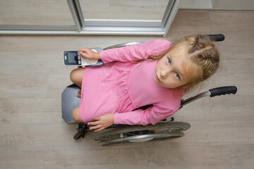 portrait of a beautiful baby girl sitting on an electric wheelchair indoors.	